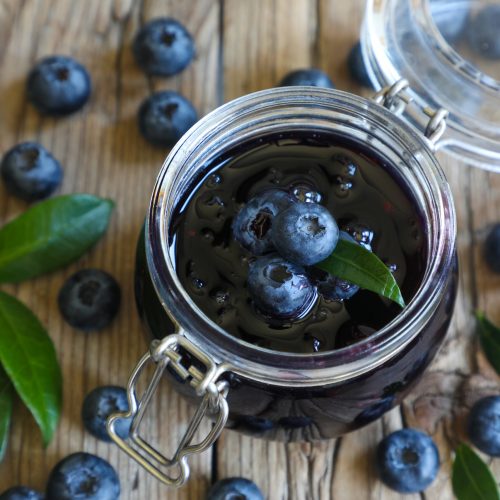 Blueberry jam in jar with berries and leaves