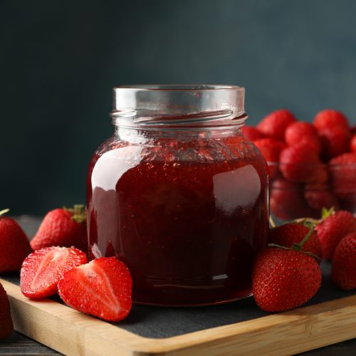 Composition with strawberry jam on wooden table, close up