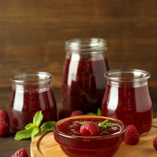 Concept of tasty food with raspberry jam on wooden background