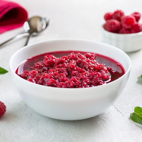 Delicious raspberry jam in a bowl on a light background. Traditional berry dessert