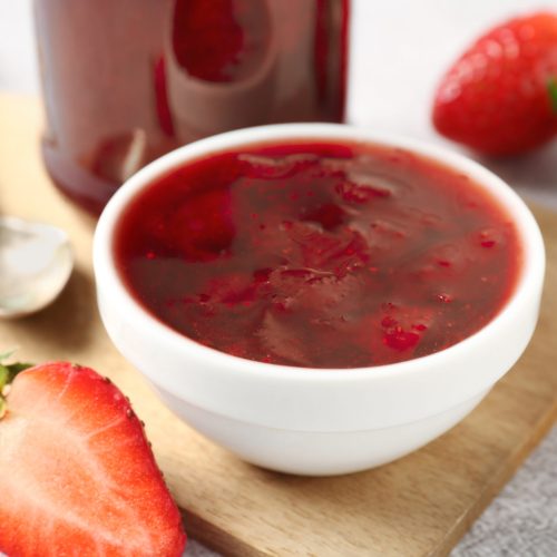 Delicious strawberry sauce and fresh berries on light table, closeup