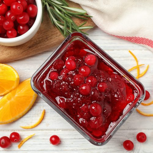 Flat lay composition with cranberry sauce and orange on white wooden table