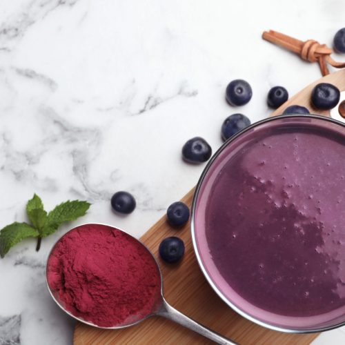 Flat lay composition with tasty acai drink, powder and berries on marble table