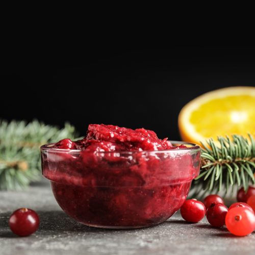 Glass bowl with tasty cranberry sauce on table